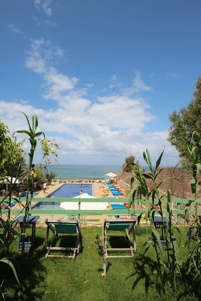 Pool and sunbeds with sea view through the trees at Side B